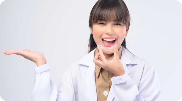 Person in a white coat smiling and holding a dental aligner.