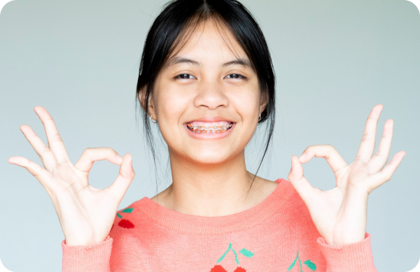 Teenager posing with traditional metal braces, showcasing a confident smile