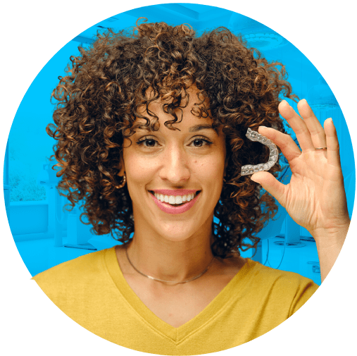A woman stands confidently, holding a invisalign in her hand, ready for her dental care routine.
