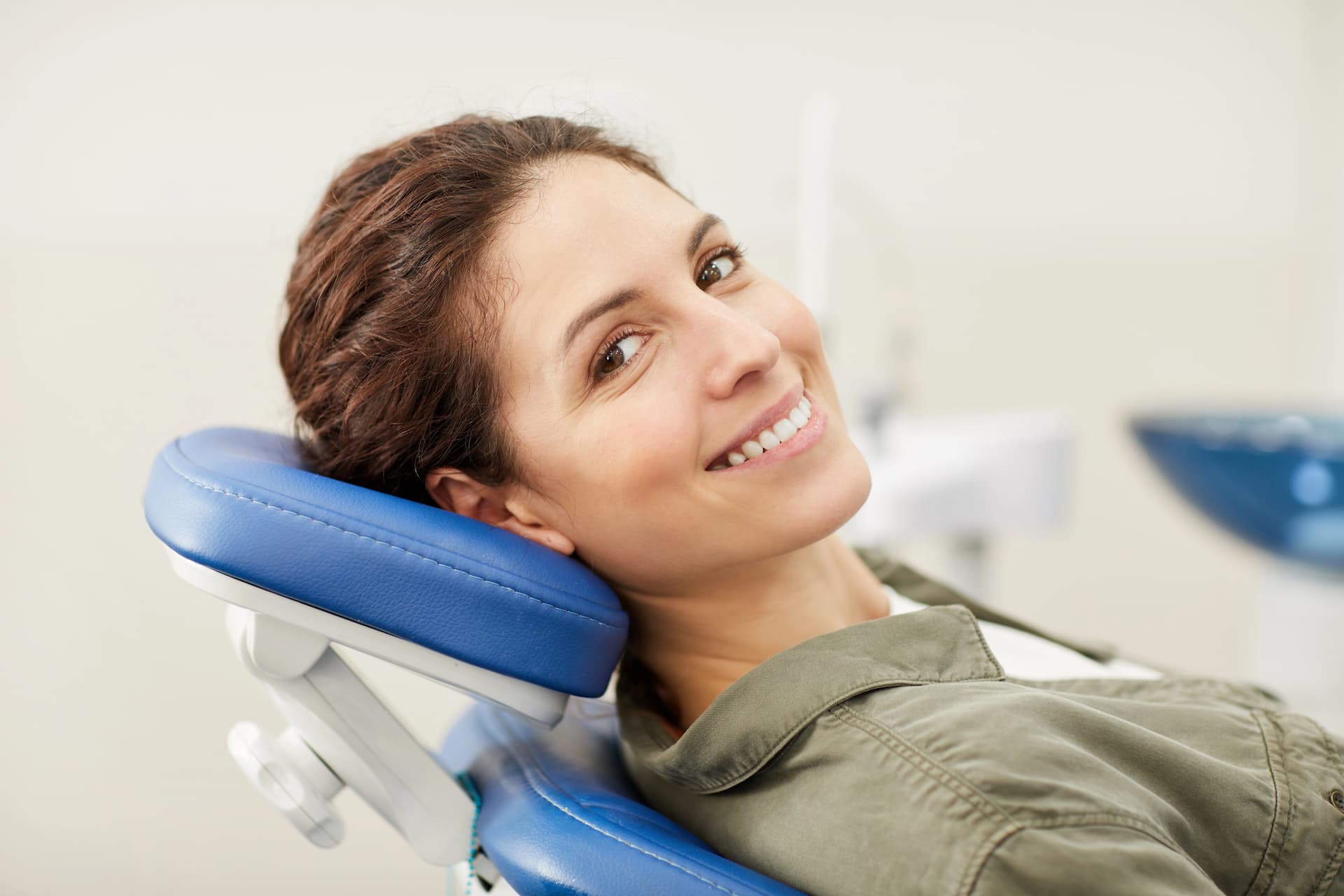 Woman smiling while sitting in a reclining dental chair in Austin