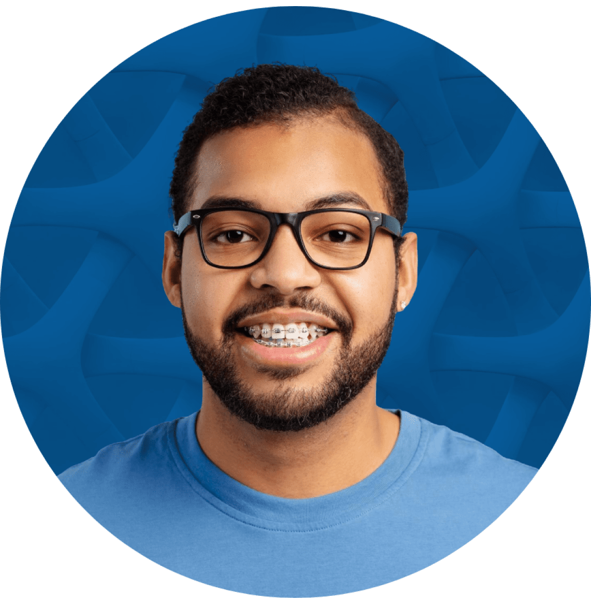 Man with glasses and braces smiling in front of a blue patterned background.