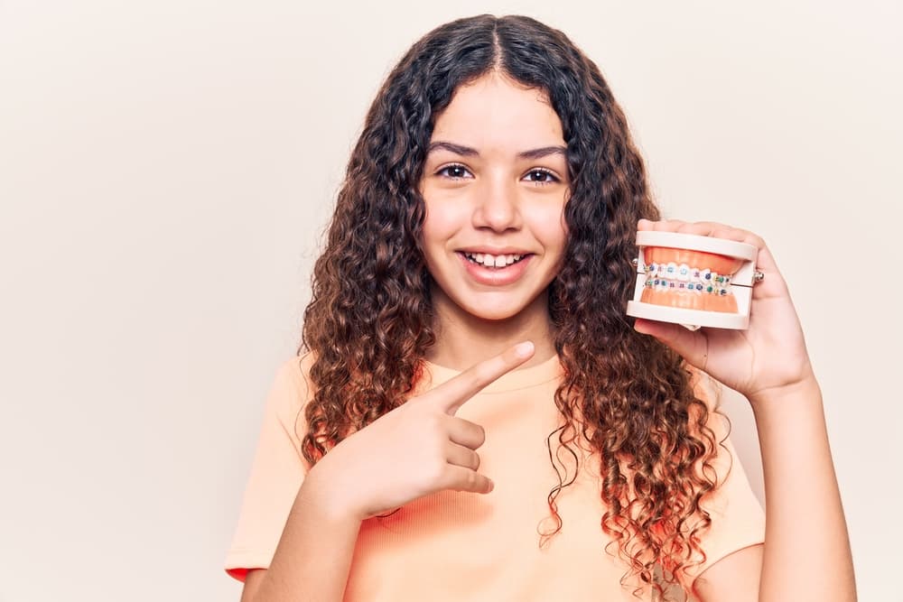 Best Orthodontics Confident young adult smiling with metal braces during an orthodontic treatment journey