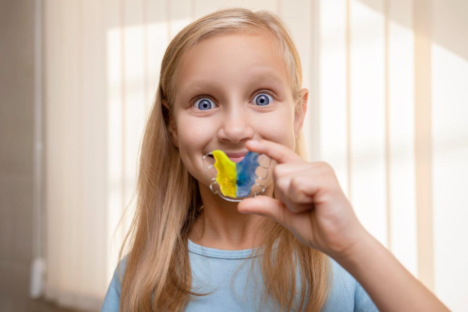 Young patient holding a removable orthodontic appliance during their bite correction treatment