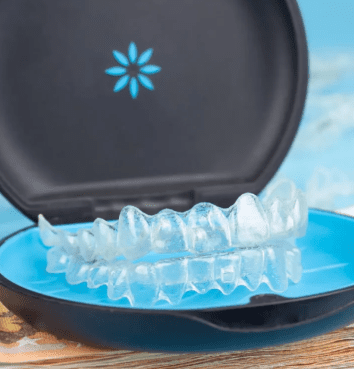 Clear aligners placed in an open black and blue case with a floral design on the lid.