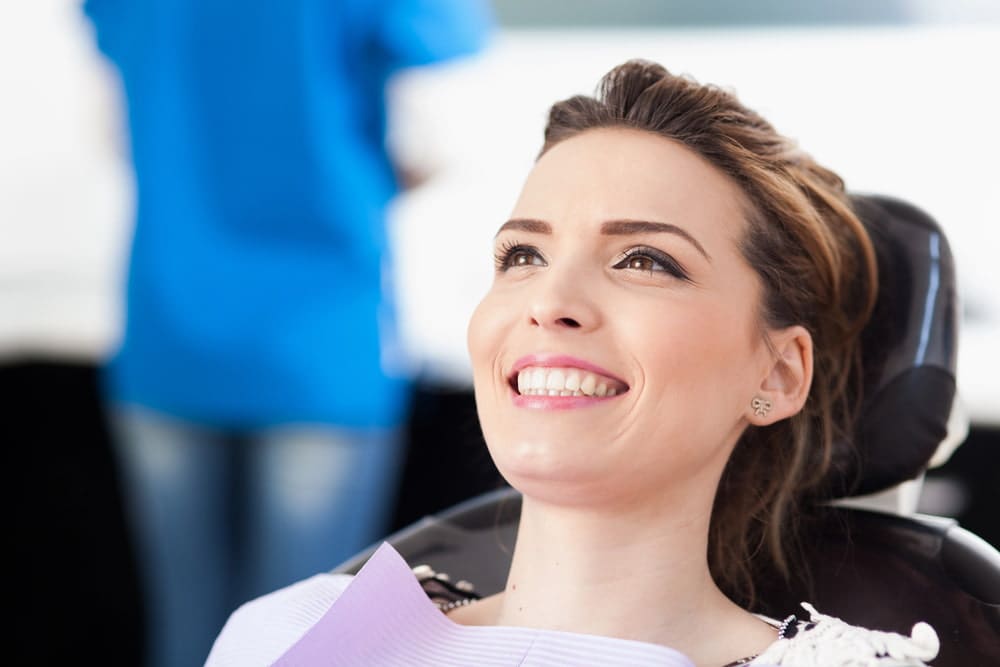 Confident young adult smiling discreetly while undergoing orthodontic treatment with lingual braces hidden behind their teeth.