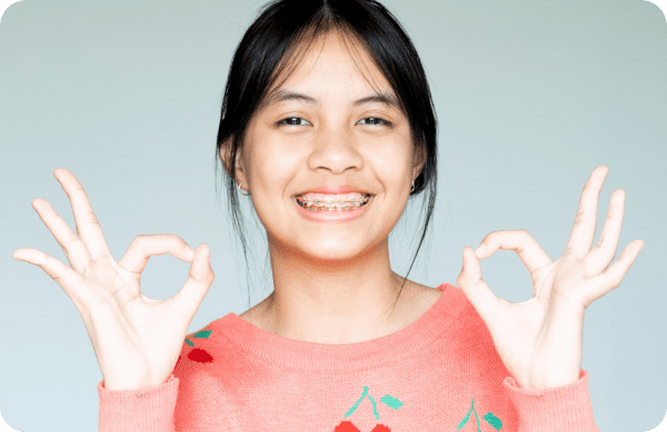 Teenager posing with traditional metal braces, showcasing a confident smile