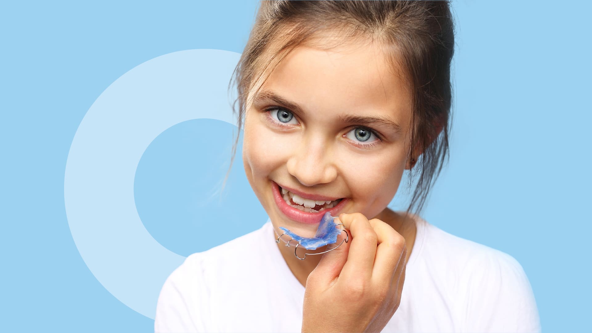 A young patient holding a set of orthodontic appliances as part of their orthodontic treatment.