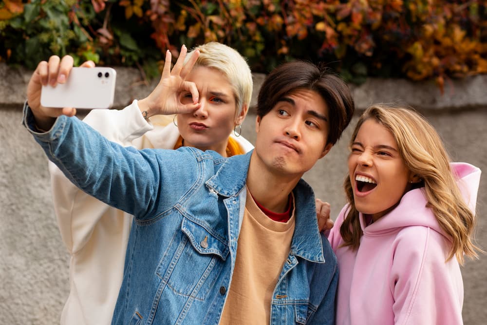 Happy young adults with braces posing for a selfie, embracing their orthodontic journey.
